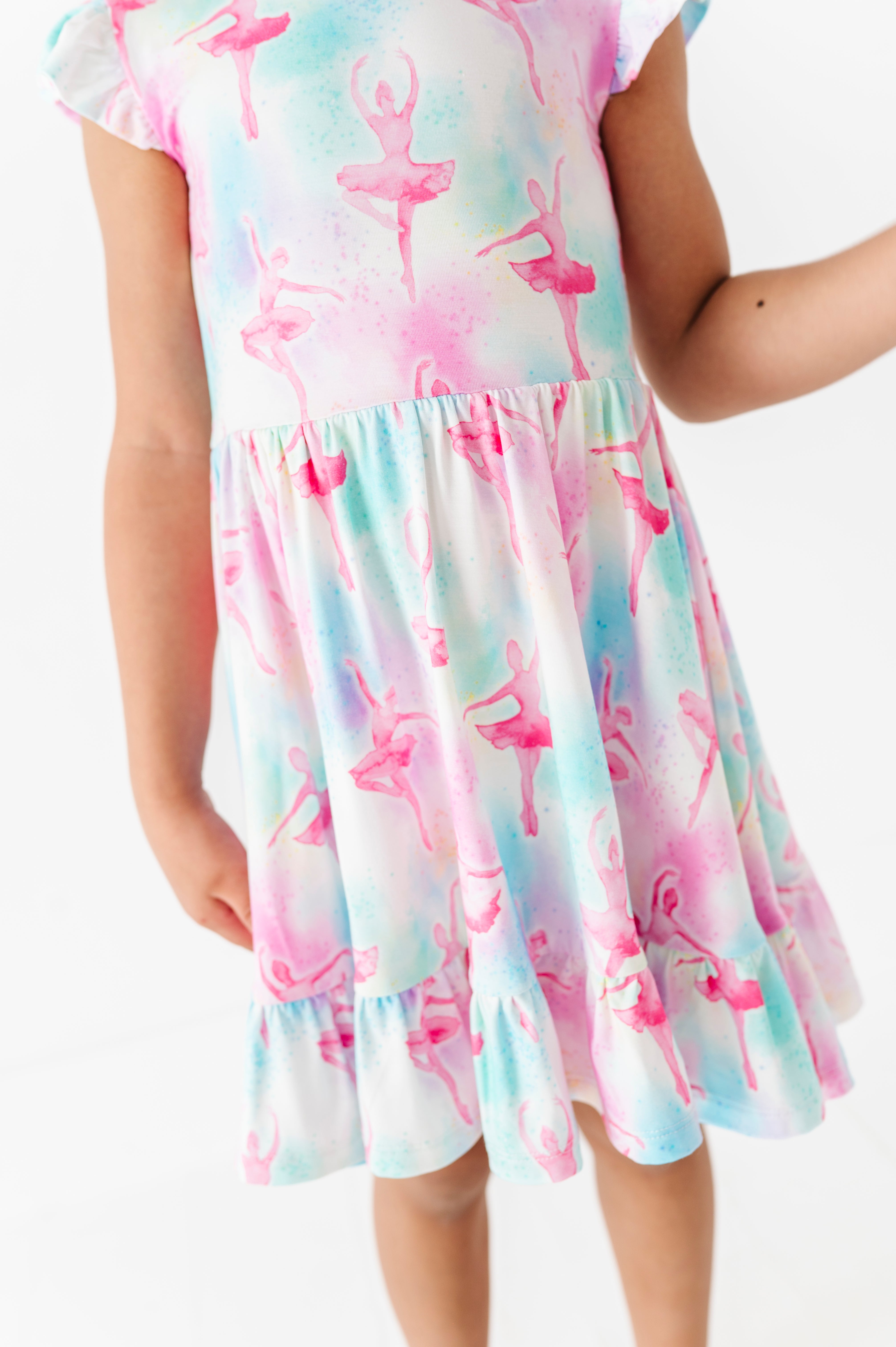 Child wearing a colorful bamboo dress with ballet dancer pattern on a white background